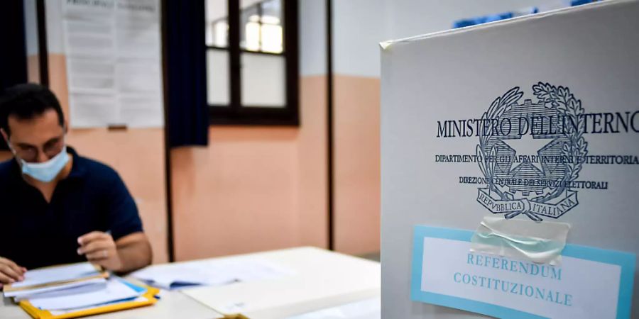 Ein Wahlhelfer sitzt an einem Tisch neben in der Parini-Mittelschule neben einer Wahlurne. Foto: Claudio Furlan/LaPresse via ZUMA Press/dpa