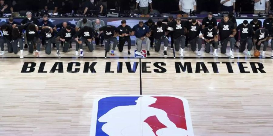 Alle Spieler der New Orleans Pelicans und von Utah Jazz knien vor einem «Black Lives Matter»-Schriftzug. Foto: Ashley Landis/Pool AP/dpa