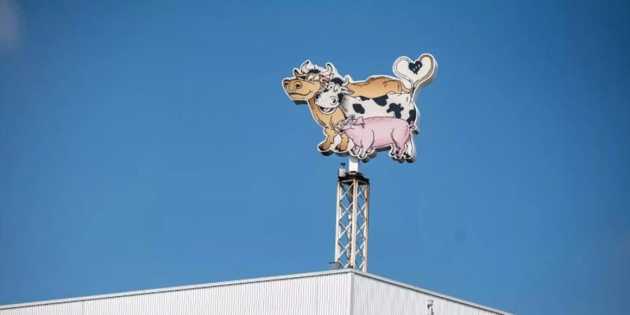 Auf dem Dach eines Gebäudes auf dem Werksgelände steht das Logo der Firma Tönnies in Form von zwei Kühen und einem Schwein. Foto: Guido Kirchner/dpa