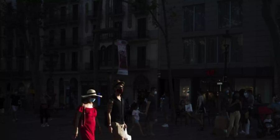 Menschen mit Mundschutz gehen auf den Las Ramblas in Barcelona. Foto: Felipe Dana/AP/dpa
