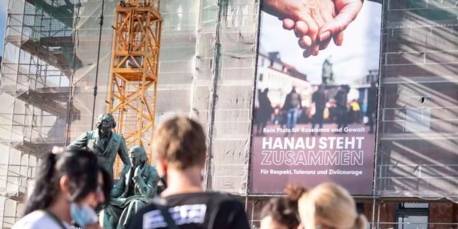 Ein neues Banner mit der Aufschrift «Kein Platz für Rassismus und Gewalt - Hanau steht zusammen für Respekt, Toleranz und Zivilcourage» hängt an der Fassade des Rathauses vor dem Gebrüder-Grimm-Denkmal. Foto: Frank Rumpenhorst/dpa