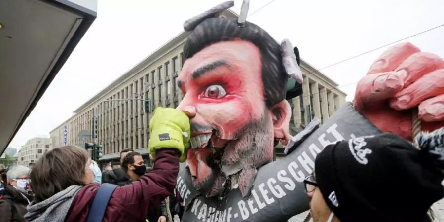 Mitarbeiterinnen und Mitarbeiter von Galeria Kaufhof schlagen am Tag der Schliessung ihrer Filiale mit Boxhandschuhen auf eine Pappfigur von Firmeneigner Rene Benko ein. Foto: Roland Weihrauch/dpa