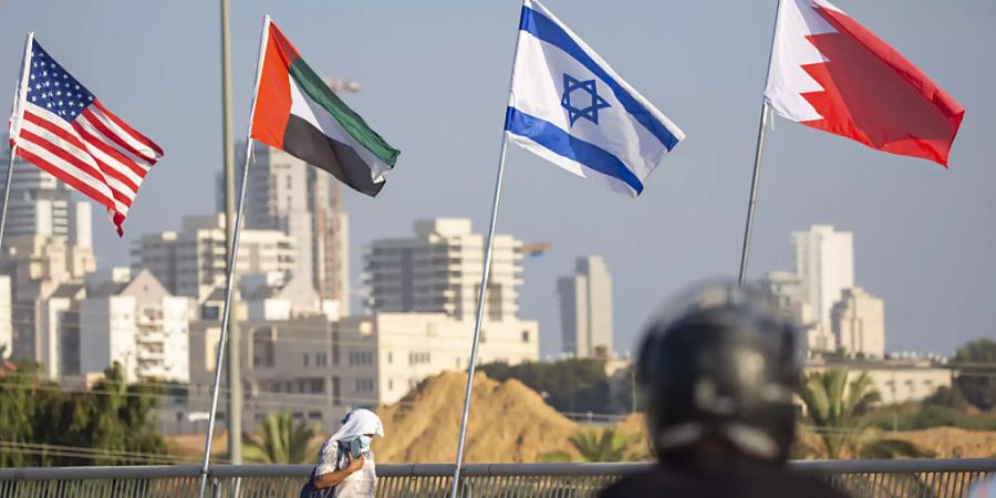 Eine Frau geht an den Flaggen der USA (l-r), der Vereinigten Arabischen Emirate, Israels und Bahrains vorbei. Foto: Ariel Schalit/AP/dpa