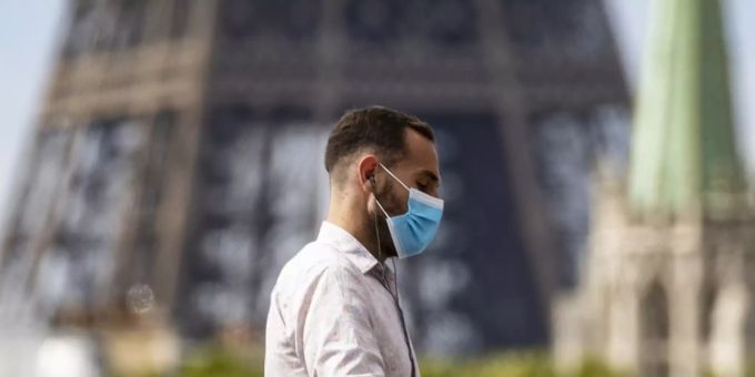 Ein Mann mit Maske vor dem Eiffelturm. Coronavirus paris Frankreich