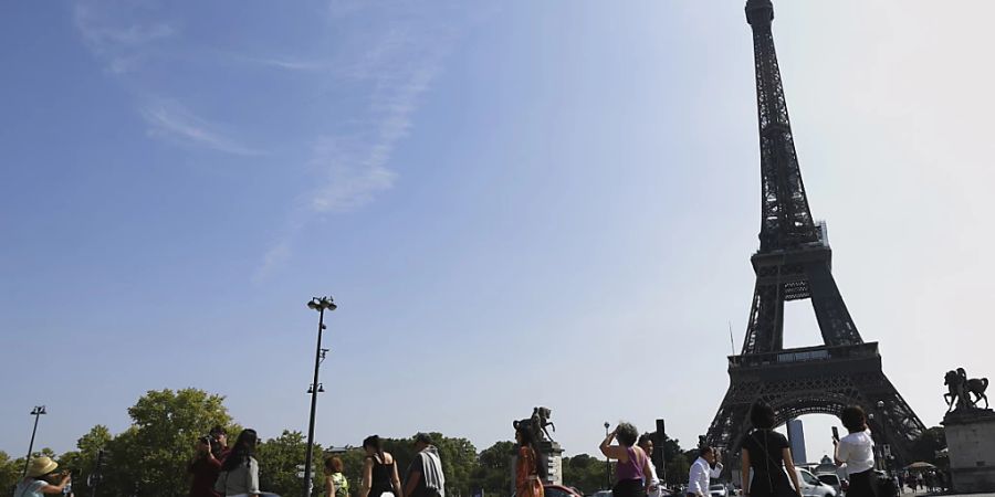 Touristen besichtigen und fotografieren den Eiffelturm. Foto: Aurelien Morissard/AP/dpa