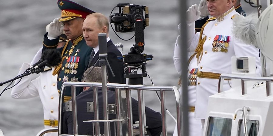 Wladimir Putin (M), Präsident von Russland, Sergej Schoigu (l), Verteidigungsminister von Russland, und Admiral Nikolai Jewmenow, Oberbefehlshaber der russischen Marine, nehmen an der grossen Marine-Parade zum Tag der russischen Marine an der Newa in St. Petersburg teil.