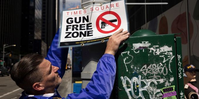 Ein New Yorker Polizist befestigt ein Schild mit der Aufschrift «Gun Free Zone» (Waffenfreie Zone). Ein New Yorker Polizist befestigt ein Schild mit der Aufschrift «Gun Free Zone» (Waffenfreie Zone).