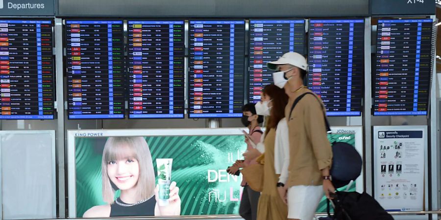 Passagiere gehen mit ihrem Gepäck an der Fluganzeigetafel des Flughafens Bangkok-Suvarnabhumi vorbei. Foto: Linda Khoo/BERNAMA/dpa