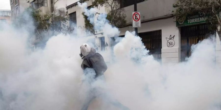 Ein Demonstrant wirft einen Tränengaskanister zurück, der von der Polizei abgefeuert wurde, um einen Protest in Santiago aufzulösen. Foto: Matias Basualdo/ZUMA Press Wire/dpa