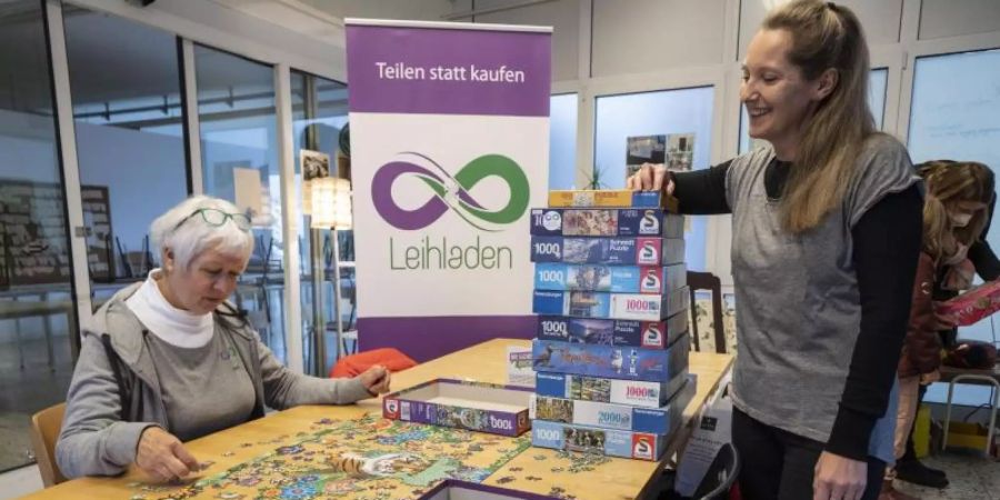 Die freiwilligen Mitarbeiterinnen Anne Deneke (l) und Dana Lorentz-Sengöz stehen vor einem Stapel Puzzles, die man ausleihen kann. Foto: Frank Rumpenhorst/dpa