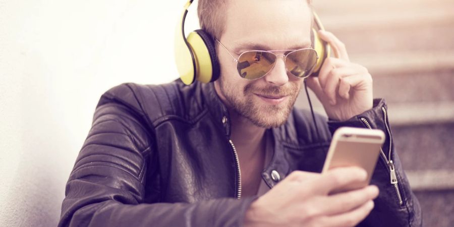 Mann hört mit Kopfhörern Musik über das Smartphone