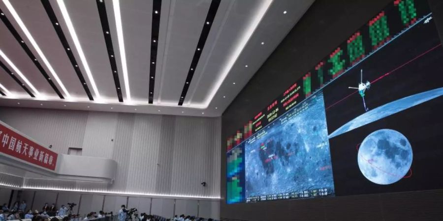 Technisches Personal überwacht den Transfer der auf dem Mond gesammelten Proben vom Aufstiegsmodul zum Rückkehrer der chinesischen Sonde «Chang'e 5» im Beijing Aerospace Control Center. Foto: Jin Liwang/XinHua/dpa