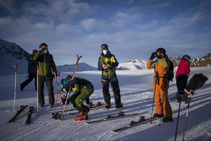 Skifahrer mit Schutzmaske machen sich in Arosa bereit für die Abfahrt. Skifahrer Schutzmaske