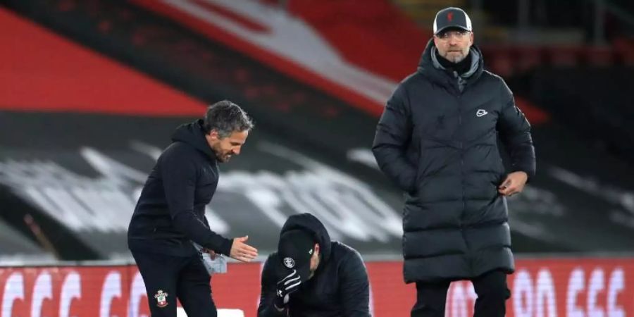 Während Southamptons Trainer Ralph Hasenhüttl (M) auf die Knie fällt zeigt sich Liverpools Trainer Jürgen Klopp (r) frustriert. Foto: Adam Davy/PA Wire/dpa