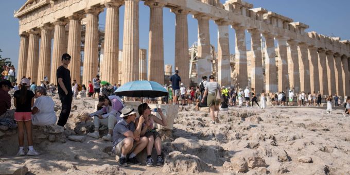 Eine Touristin trinkt Wasser unter einem Sonnenschirm in der Hitze von Athen. Hitze