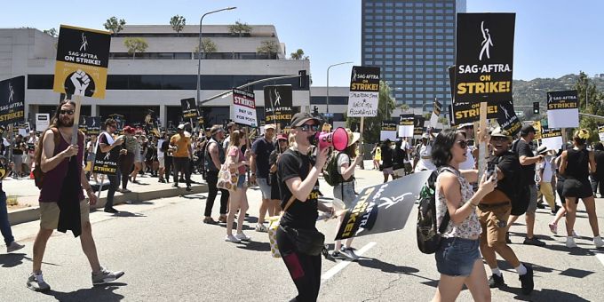 Personen halten Schilder an der Streikpostenkette vor den Universal Studios in Universal City. Der Streik der Schauspieler findet mehr als zwei Monate nach dem Streik der Drehbuchautoren statt, die sich für bessere Bezahlung und Arbeitsbedingungen einsetzen. Foto: Richard Shotwell/Invision/AP/dpa Personen halten Schilder an der Streikpostenkette vor den Universal Studios in Universal City. Der Streik der Schauspieler findet mehr als zwei Monate nach dem Streik der Drehbuchautoren statt, die sich für bessere Bezahlung und Arbeitsbedingungen einsetzen. Foto: Richard Shotwell/Invision/AP/dpa