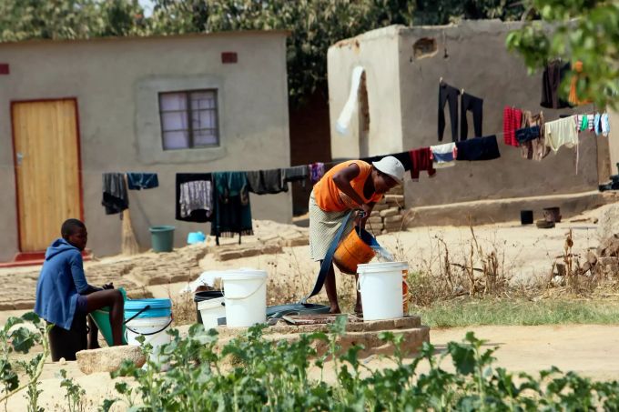 Eine Frau schöpft Wasser aus einem Brunnen in Eimer ab. Der Hauptstadt des afrikanischen Krisenstaats Simbabwe geht das Trinkwasser aus. Ursache ist die akute Devisenknappheit des Landes, die den Import von Chemikalien für die Wasseraufbereitung behindert. Das Land im südlichen Afrika steht seit Jahren am Rande des Kollapses seiner Infrastruktur. Foto: Tsvangirayi Mukwazhi/AP/dpa +++ dpa-Bildfunk +++ Simbabwe