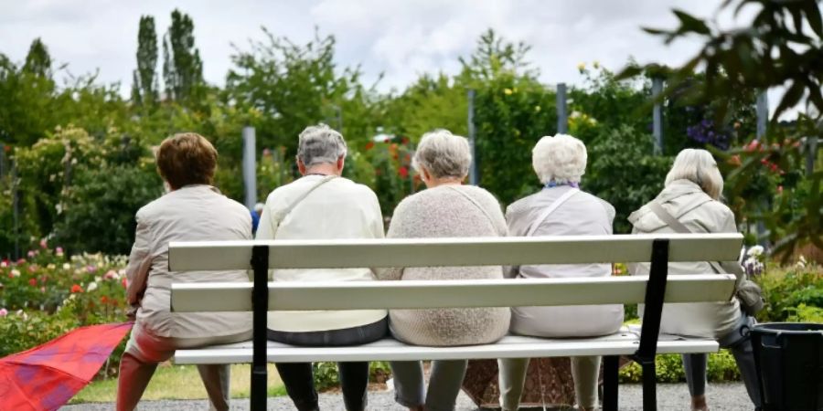 Fünf ältere Frauen sitzen auf einer Parkbank