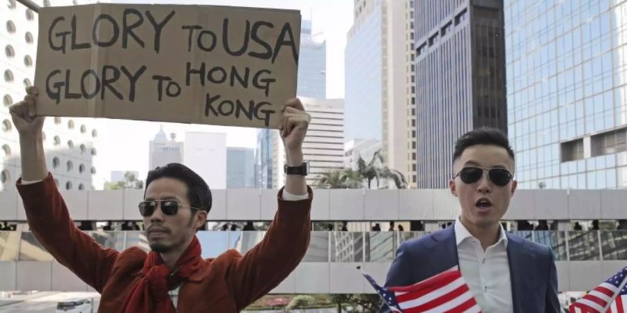 Demonstranten halten amerikanische Flaggen und ein Plakat mit der Aufschrift «Glory to USA, Glory to Hong Kong» («Ruhm für die USA, Ruhm für Hong Kong») hoch. Foto: Kin Cheung/AP/dpa