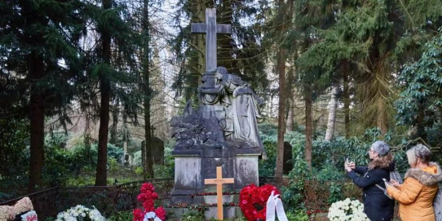 Zwei Frauen stehen am Grab von Jan Fedder auf dem Ohlsdorfer Friedhof. Foto: Georg Wendt/dpa