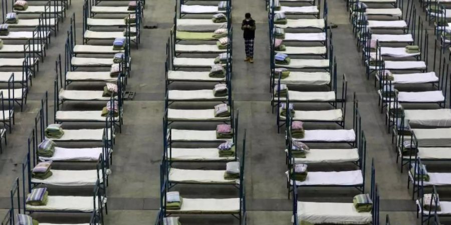 Ein Mitarbeiter steht zwischen Feldbetten, die in einem Kongresszentrum in Wuhan aufgestellt wurden. Es fehlen Betten zur Behandlung von Infizierten. Foto: -/CHINATOPIX/AP/dpa