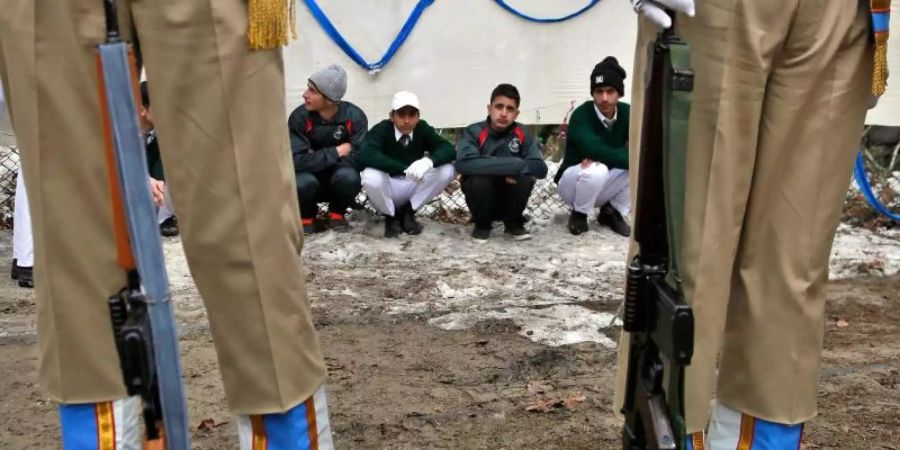 Indische Soldaten vor Schülern aus Kaschmir während einer Parade zum indischen Nationalfeiertag. Foto: Mukhtar Khan/AP/dpa