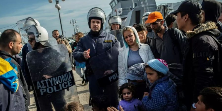 Griechische Polizisten und Migranten am Hafen von Lesbos