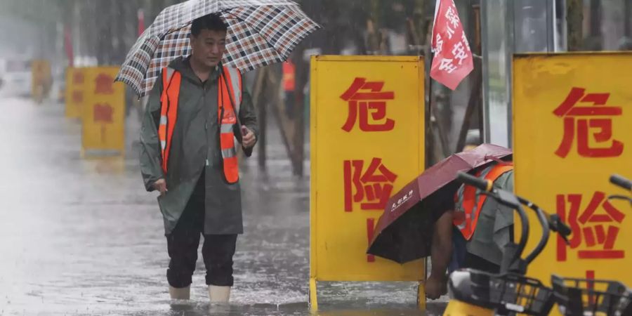 Ein Mann watet durch die Wassermassen nach Einsetzen des Starkregens in Zhengzhou.