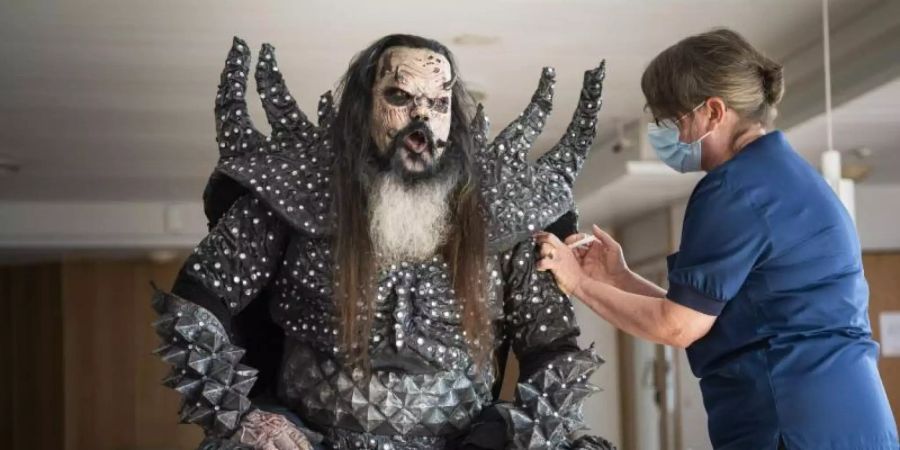 Mr. Lordi, Sänger der finnischen Hard-Rock-Band Lordi, wird von der Krankenschwester Paula Ylitalo geimpft. Foto: Jouni Porsanger/Lehtikuva/dpa