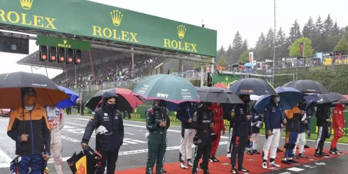 Die Fahrer stehen vor dem Start zusammen im Regen. Formel 1 Spa