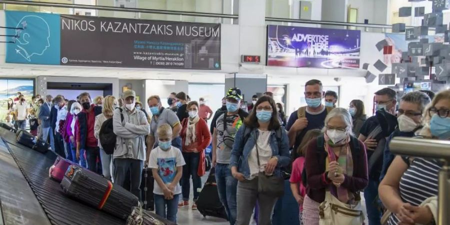 Passagiere aus Hannover warten am internationalen Flughafen Nikos Kazantzakis auf Kreta auf ihr Gepäck. Foto: Harry Nakos/AP/dpa