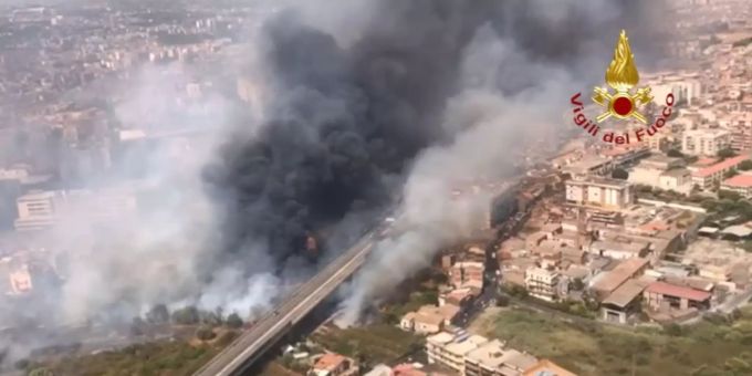 HANDOUT - 30.07.2021, Italien, Catania: Blick aus einem Hubschrauber der Feuerwehr auf Brände neben der Via Palermo - dichter Rauch zieht über die Wohnhäuser. In Italien sind die Feuerwehren weiter im Dauereinsatz gegen die lodernden Waldbrände. Allein in Sizilien rückten die Retter 250 Mal aus. Foto: -/Vigili del Fuoco/dpa - ACHTUNG: Nur zur redaktionellen Verwendung im Zusammenhang mit der aktuellen Berichterstattung und nur mit vollständiger Nennung des vorstehenden Credits +++ dpa-Bildfunk +++ Waldbrände auf Sizilien