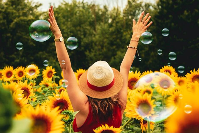 Wer einen starken Willen zur Veränderung hat, schafft es eher, seine Vorsätze umzusetzen. Frau in Sonnenblumenfeld