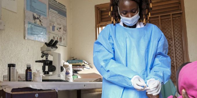 Eine Gesundheitsmitarbeiterin in Uganda nimmt eine Blutprobe bei einem Kind. Uganda