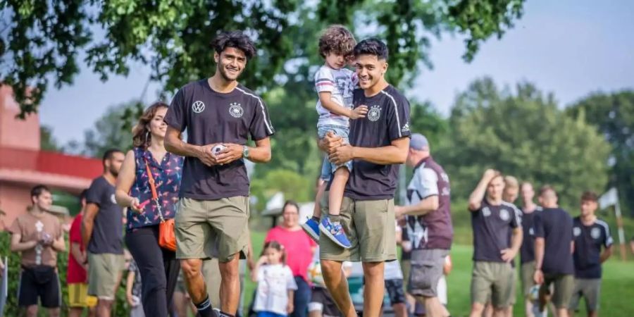 Mahmoud Dahoud (l) und Nadiem Amiri mit einer Gruppe krebskranker Kinder im DFB-Teamhotel in Fagagna. Foto: Sung-Bin Hong/DFB