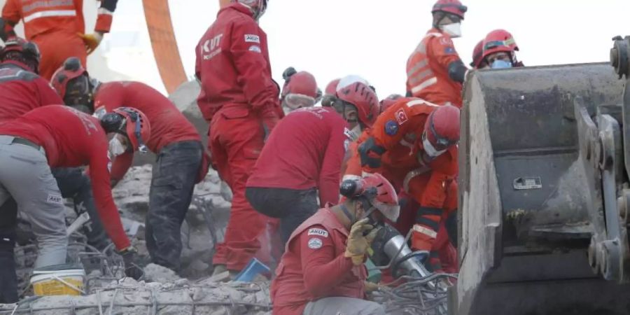 Rettungskräfte suchen in den Trümmern eines eingestürzten Gebäudes in Izmir nach Überlebenden. Foto: Darko Bandic/AP/dpa