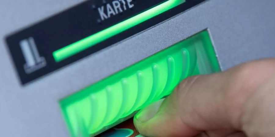 Eine Bankkundin steckt ihre Girokarte in einen Geldautomaten. Foto: Fabian Sommer/dpa/Symbolbild/Archiv
