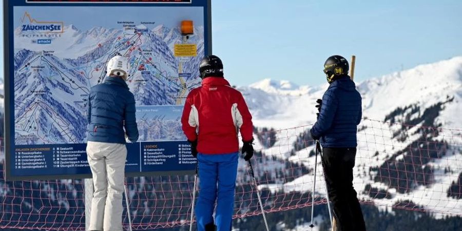 Skifahrer vor einer Informationstafel mit der Aufforderung nach FFP2-Masken und 2G-Nachweis im Skigebiet Altenmarkt-Zauchensee. Foto: Barbara Gindl/APA/dpa