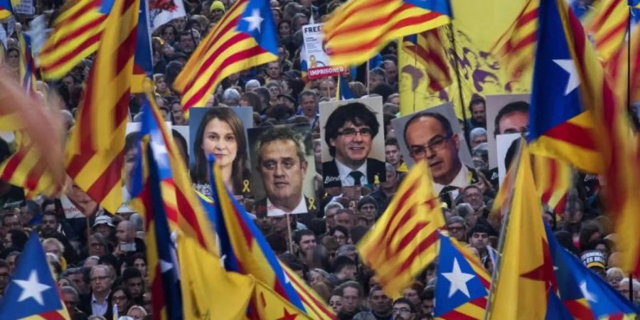 Demonstranten tragen bei der Massenkundgebung in Barcelona Fahnen und Bilder ehemaliger katalanischer Regierungmitglieder. Foto: Emilio Morenatti/AP
