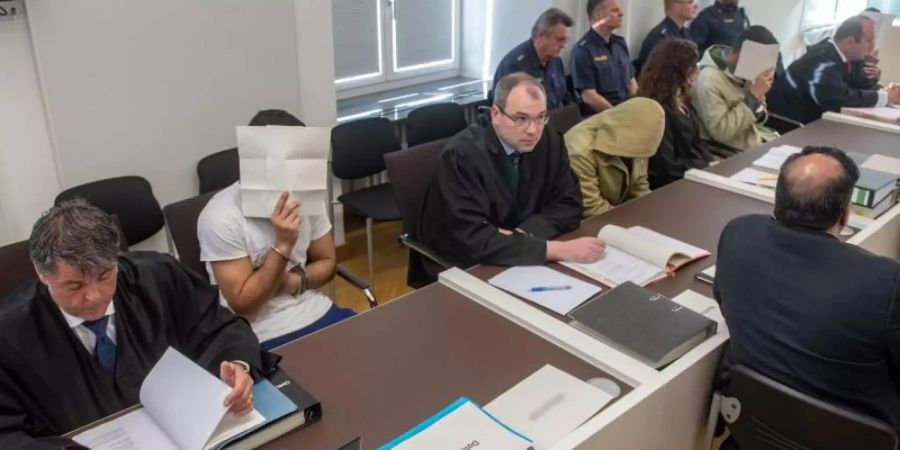 Die vier Angeklagten sitzen neben ihren Anwälten im Verhandlungssaal des Amberger Amtsgerichts. Foto: Armin Weigel