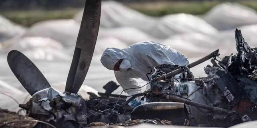 Ein Experte untersucht das ausgebrannte Flugzeugwrack. Foto: Boris Roessler