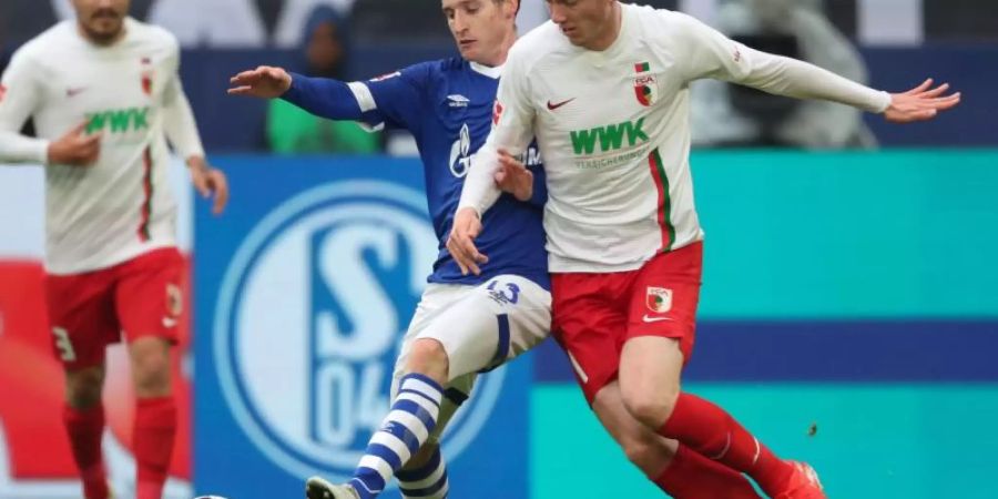 Schalkes Sebastian Rudy (l) spitzelt den Ball vor Augsburgs Michael Gregoritsch weg. Foto: Friso Gentsch