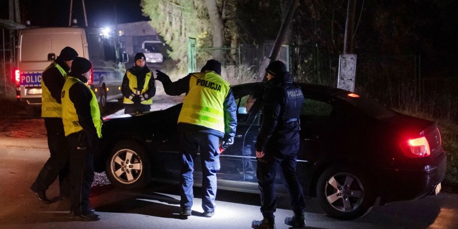 Polizisten versammeln sich vor einem Getreidelager in Przewodow im Südosten Polens. Nach einer Explosion mit zwei Toten hat Polen einen Teil seiner Streitkräfte in erhöhte Bereitschaft versetzt.