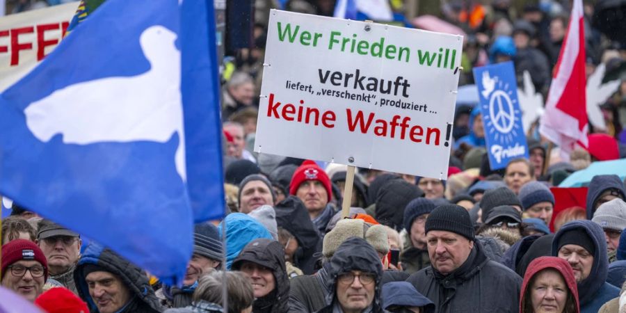 Ein Teilnehmer der Demonstration hält einen Schild mit der Aufschrift «Wer Frieden will verkauft, liefert, «verschenkt», produziert keine Waffen».