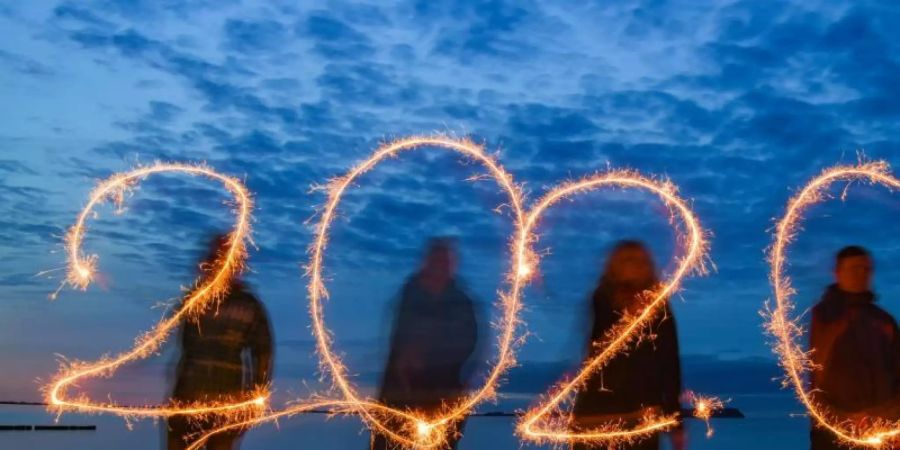 Vier Personen schreiben mit Wunderkerzen die Jahreszahl 2020 in den Abendhimmel. Foto: Patrick Pleul/dpa-Zentralbild/dpa