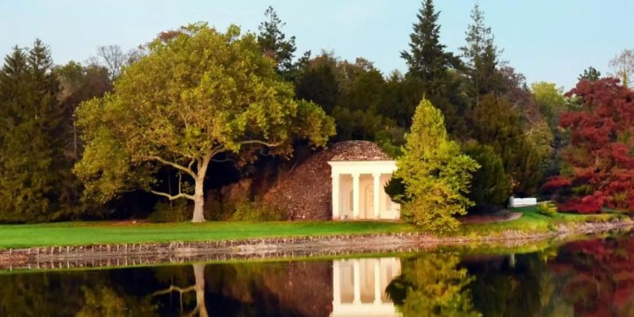 Goldener Oktober: Herbstlich gefärbte Bäume und das Nymphaeum spiegeln sich im See im Wörlitzer Park. Foto: Waltraud Grubitzsch/dpa-Zentralbild/dpa