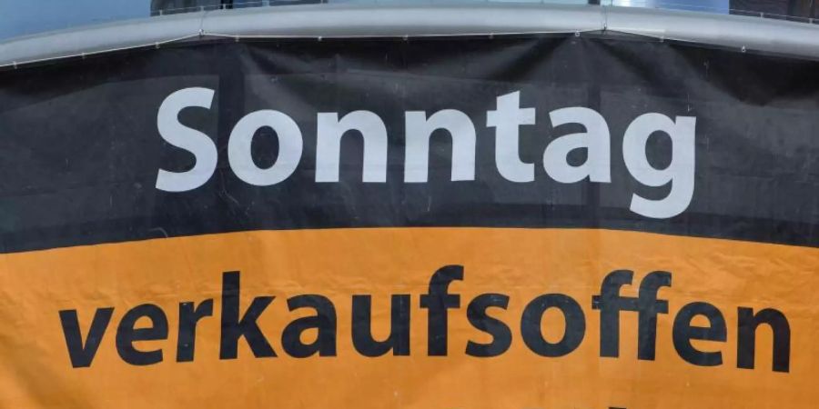 Ein Werbeposter informiert über die Öffnungszeiten an einem verkaufsoffenen Sonntag. Foto: Jens Büttner/zb/dpa
