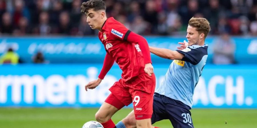 Leverkusens Kai Havertz (l) im Duell mit Gladbachs Nico Elvedi. Foto: Marius Becker/dpa