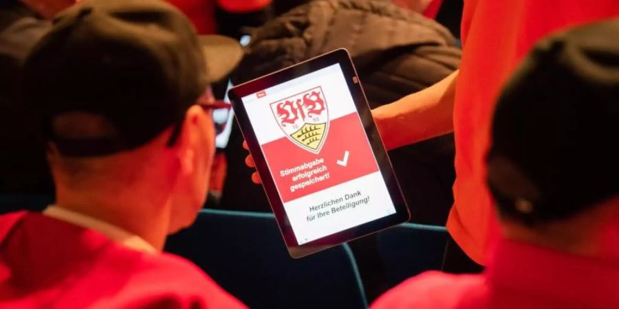 Mitglieder des VfB Stuttgart stimmen in der Hanns-Martin-Schleyer-Halle mit einem Tablet ab. Foto: Tom Weller/dpa