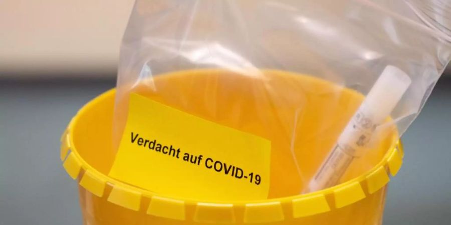 Ein Teströhrchen liegt in einer Tüte mit der Aufschrift "Verdacht auf COVID-19". (Symbolbild). Foto: Marius Becker/dpa